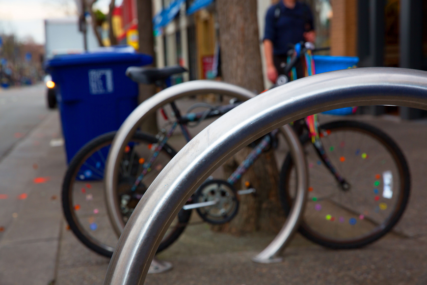 A brightly decorated bike is attached to stainless steel ring bike parking