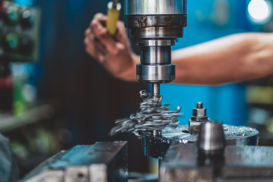 A machinist operates a milling machine by hand