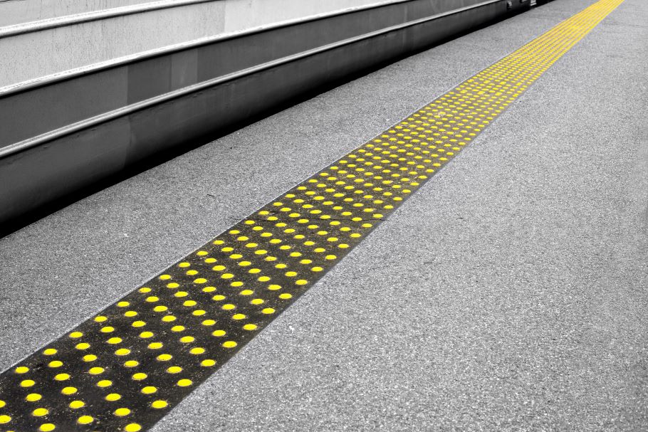 Domes in yellow on a black plate warn users of a gap at the subway