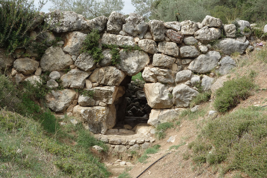 An old stone bridge with an arch is made of large, weathered boulders