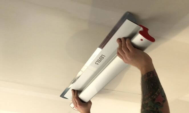 A LEVEL5 32-Inch Drywall Skimming Blade applying a skim coat to a ceiling.