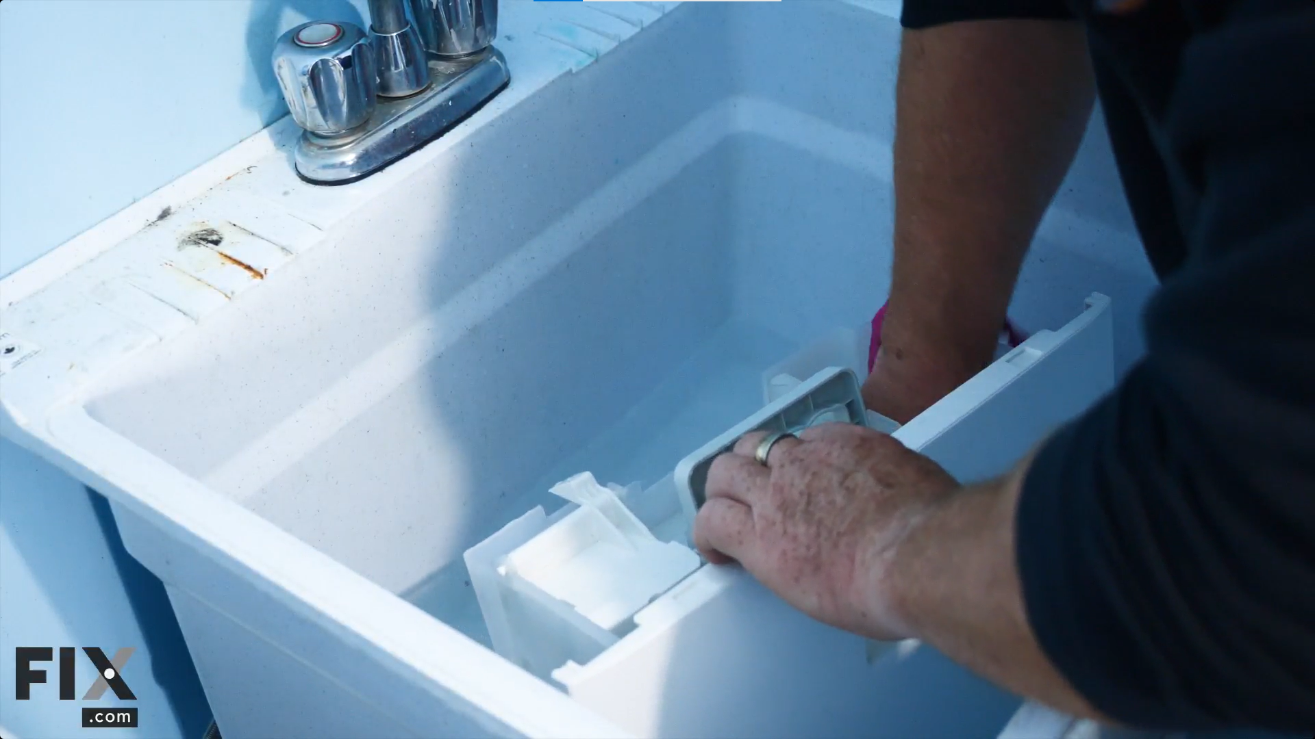 A technician is soaking a dehumidifier's reservoir in a sink with water and vinegar, then wiping it with a pink cloth.